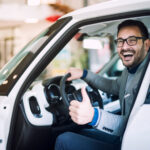 Hombre feliz con pulgar arriba dentro de vehículos usados