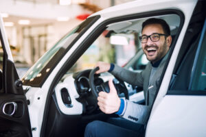 Hombre feliz con pulgar arriba dentro de vehículos usados